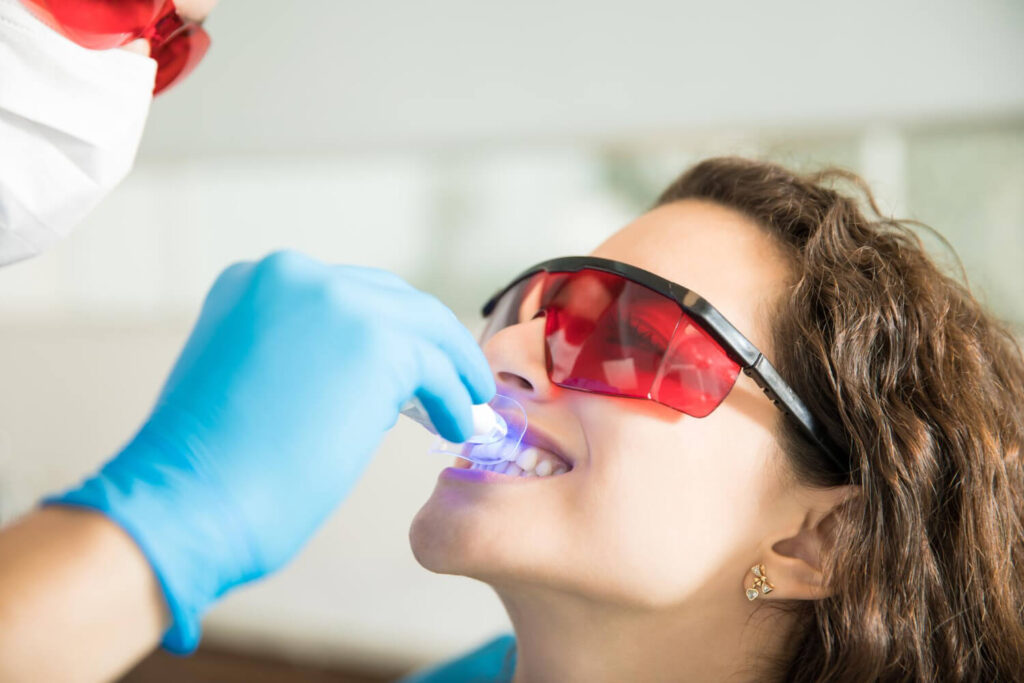 Dentista realiza clareamento dental de consultório com aplicação de luz em paciente na Nakamura Odontologia Plena, em Barreiras BA.