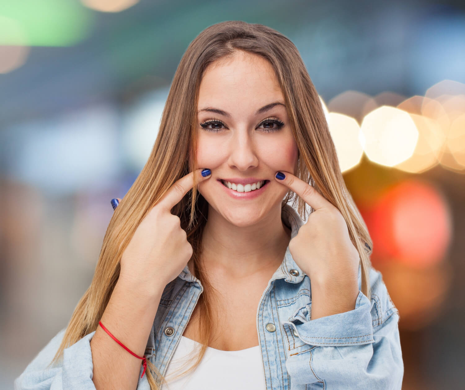 Mulher sorrindo aponta para o sorriso saudável, ilustrando a recuperação de implante dentário na Nakamura Odontologia em Barreiras BA.