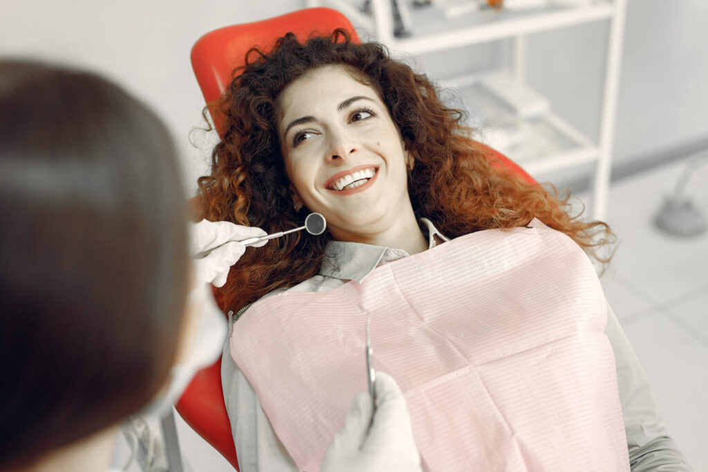Mulher na cadeira de dentista sorri durante consulta de dente com canal tratado na Clínica Nakamura Odontologia Plena em Barreiras - BA.